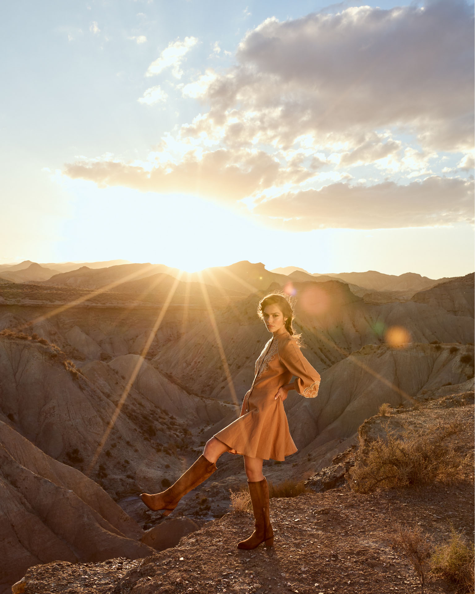 Fotografía de una modelo con el fondo del desierto de tabernas en Almería con botas altas de la firma Porronet
